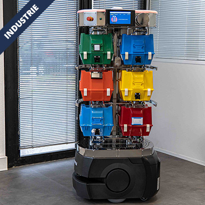 Autonomous waste-collection robot with a vertical rack of six colored bins (green, blue, orange, yellow, blue, red) in an industrial setting.