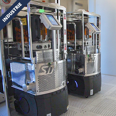 Two stainless steel industrial machines with touchscreens, side by side in a factory setting, used for automated production.