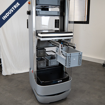 Autonomous warehouse robot retrieving a gray plastic crate from a shelving unit in an industrial setting.