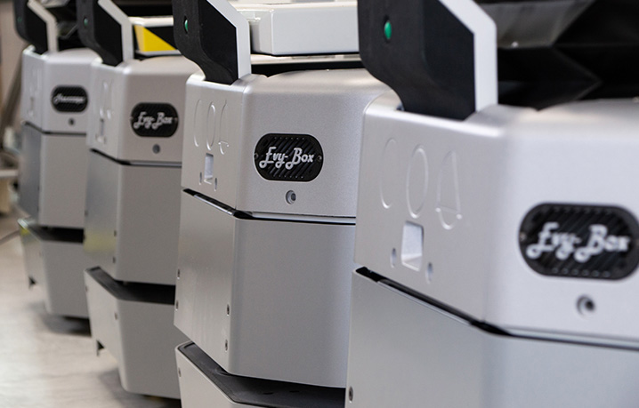 Row of identical gray industrial printers lined up in a factory setting.