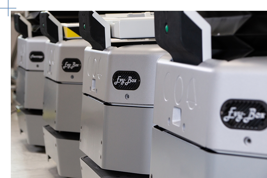 Row of Fly-Box industrial machines lined up in a lab, showing front panels with logos.