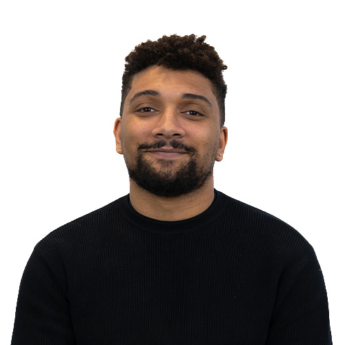 Portrait of a man with short dark hair and a trimmed beard, wearing a black knit sweater, smiling against a white background.